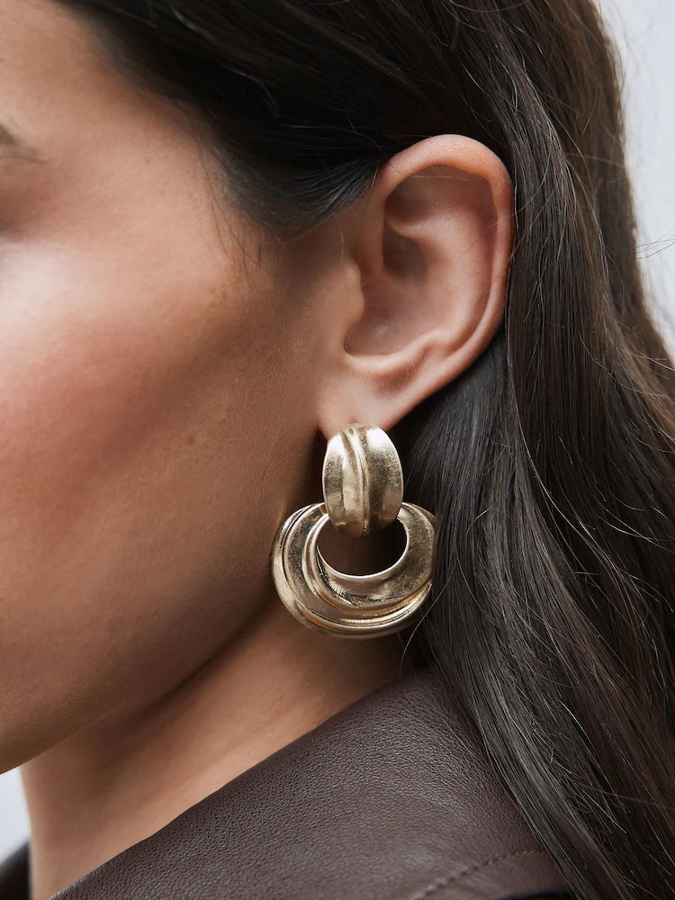 Gold-colored statement hoop earrings with pendants